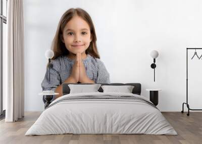 Little girl praying to God with folded hands. Child's prayer, close-up on white background. Concept: Christian religion, faith in Jesus Christ. Wall mural