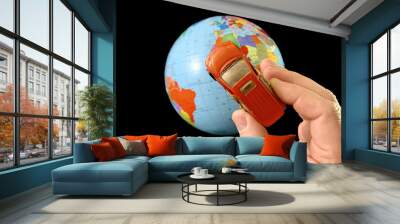 Toy car in hand on a background of the globe. Man with a car model, on a black background. A man points his hand to the globe. Concept: travel, tourism Wall mural