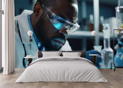 A Black man wearing safety glasses and gloves conducts an experiment in a laboratory. Wall mural