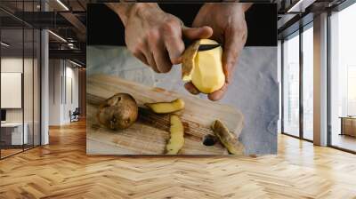 The chef cleans potatoes. For dishes with potatoes. On a black background, the concept of the menu, cooking, healthy eating Wall mural