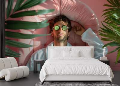 Relaxed man in white bathrobe lying on a pink chair with cucumbers on eyes, spa Wall mural