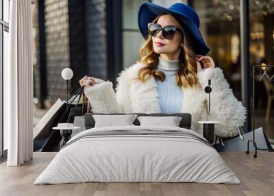 Photo of pretty millennial lady carry many packs shopper tourism abroad look unbelievable sales low prices mall wear fluffy jacket sun specs blue hat Wall mural