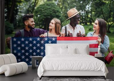 Happy  four students relaxing on nature with american flag, celebrating 4th july - Independence Day. After education. Wall mural