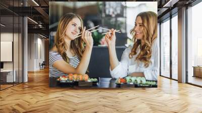 Lunch at a Chinese restaurant on the summer terrace. Mom and her young beautiful daughter eat sushi with chinese sticks Wall mural