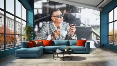 Stylish attractive senior in summer terrace chilling with cup of latte and looking forward to Wall mural