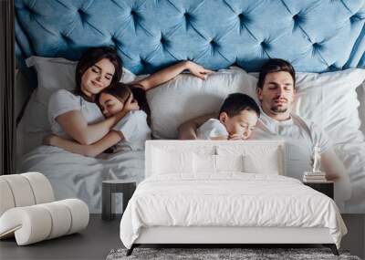 Top wiev of sleepy family with children lying on bed.. Wall mural