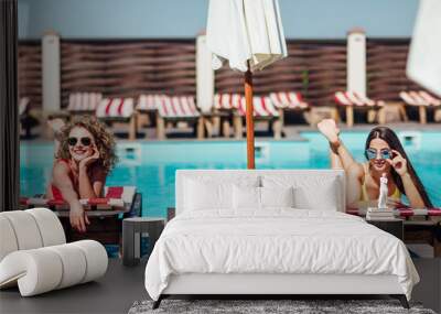 Two  pretty sexy young women relaxing on deck chair  near poool. Nice time. Wall mural