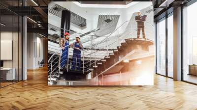 Two successful engineers discussing work together in big office with stairs. Wall mural