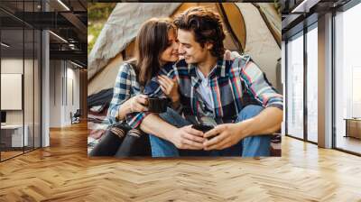 young beautiful couple in casual dress sitting in a campsite near the tent. attractive woman and han Wall mural