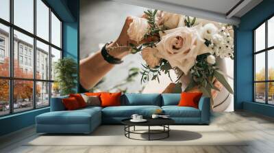 Florist working on creating bouquet in his shop, close-up photo of hands Wall mural