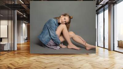 very young charming barefooted woman teenager girl sitting in studio on gray background, head on knee. Skin care leg concept in adolescence Wall mural