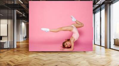 Cute little girl workout in a  leotard on a pink background. Space for text. Wall mural