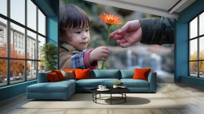 Little boy offering a gerbera to a stranger in a park, with a waterfall in the background Wall mural