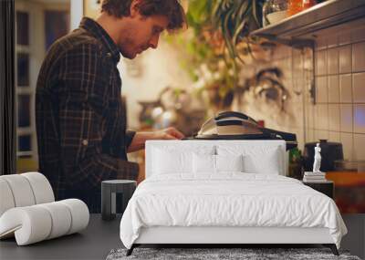 Young man is carefully closing a modern electric pressure cooker in a kitchen full of cooking ingredients Wall mural