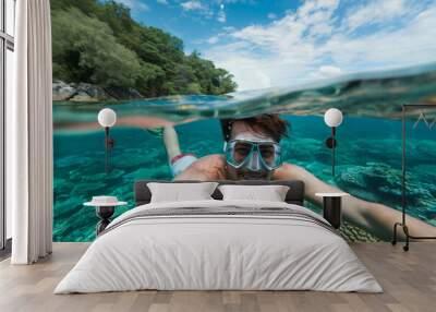 Young man takes a half-submerged selfie while snorkeling in a tropical sea Wall mural