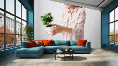 A young woman transplants a houseplant. The concept of plant care Wall mural