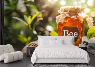 A glass jar filled with golden honey placed on a wooden table surrounded by green leaves and a honey dipper in the warm afternoon sunlight Wall mural