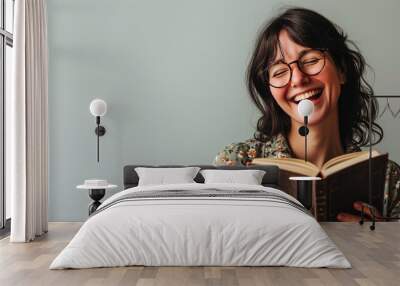 A woman laughs joyfully while reading a book Wall mural