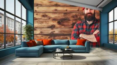 Bearded caucasian man in red plaid shirt and beanie stands against wooden background Wall mural