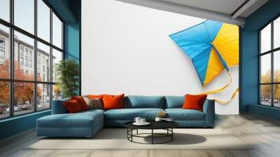 Blue and yellow kite with tails against white background Wall mural