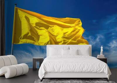 Bright yellow flag waving against blue sky Wall mural