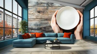 Hands holding white empty bowl on rustic wooden table Wall mural