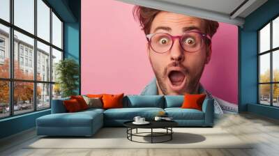 Surprised young Caucasian man with glasses against pink background Wall mural