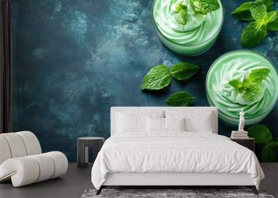 Two green mint desserts garnished with fresh leaves on textured blue surface Wall mural