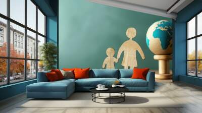 Wooden cutouts of adult and child standing beside small globe on pedestal, symbolizing global family concepts Wall mural