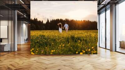 Running loving couple in the field. Sunset. Wall mural