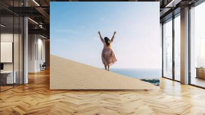 Woman in long dress enjoys on sand dune. Wall mural