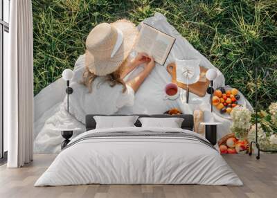 Woman read book on picnic in field. Wall mural