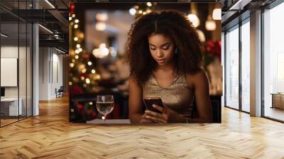 Photo of an African American young woman sitting at a table in a restaurant. The girl is holding a smartphone in her hands. Wall mural