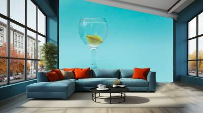 Yellow fish in a glass on a blue background Wall mural