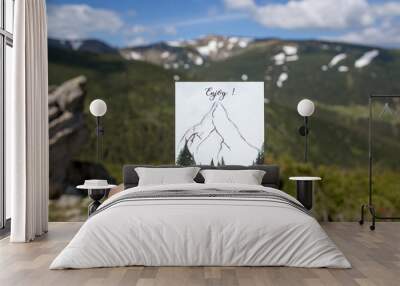 The travel postcard in the hand with background of mountains, adventures in the mountains, enjoy the moment Wall mural