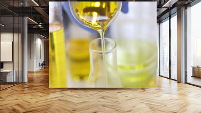 Scientist's hand in rubber glove pours yellow liquid into glass test tube in chemical laboratory closeup. Drug production pharmaceutical technology concept. Wall mural