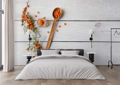 Top view sea buckthorn berries on white wood background with wooden spoon Wall mural