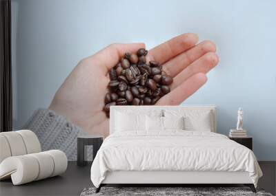 Roasted coffee beans in hand on a white background. A woman's hand with black coffee. Open palm. Wall mural