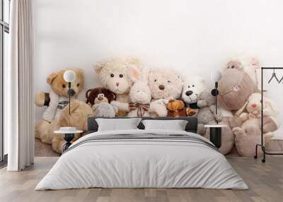 Many soft toys are sitting on the background of a white wall Wall mural