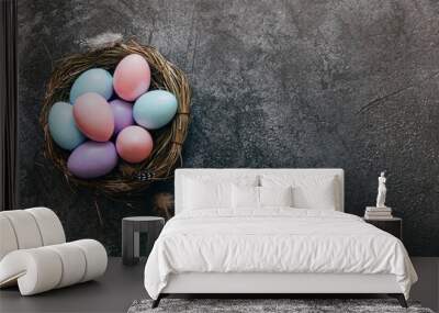 Happy Easter concept. Preparation for holiday. Colorful pastel decorated easter eggs in nest on grunge scratched dark black shale background. Simple minimalism flat lay top view copy space Wall mural