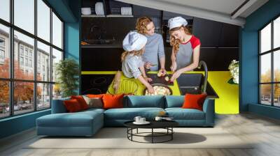 Happy family in kitchen. Mother and two children preparing dough, bake apple pie. Mom and daughters cooking healthy food at home and having fun. Household, teamwork helping, maternity concept Wall mural