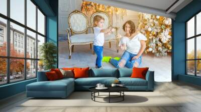 Happy family woman mother and little girl relax playing sparkler near Christmas tree on Christmas eve at home. Mom, daughter in light bedroom with winter decoration. Christmas New Year time  Wall mural