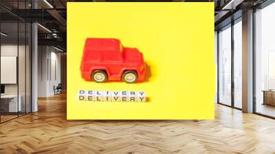 Simply design red toy car and inscription DELIVERY word isolated on yellow colorful background. Internet shopping online purchase e-commerce packages delivery service concept Copy space Wall mural