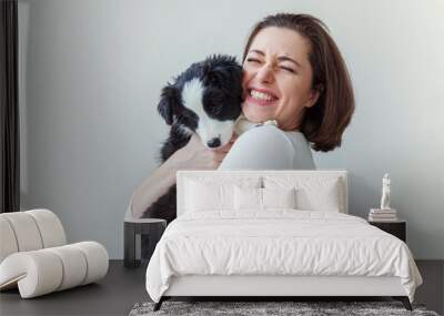 Smiling young attractive woman embracing cute puppy dog border collie isolated on white background. Girl huging new lovely member of family. Pet care and animals concept Wall mural