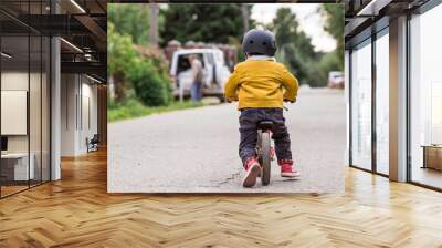 A cheerful little boy rides a running bike in a helmet outdoors. A happy child is engaged in an active sport. Protection. Life insurance and child safety. Wall mural