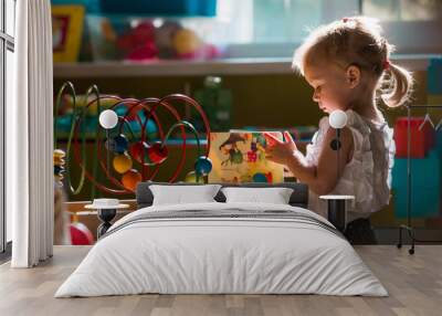 A cute little girl of 3 years old is playing educational toys in a kindergarten group. Portrait of a child. Wall mural