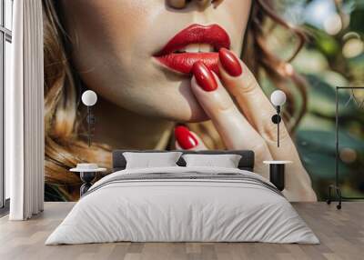 A sexy woman touching her painted red lips with a manicure on her red nails. Cosmetic products, fashionable lipstick, lip gloss and nail polish. A sensual woman. Wall mural