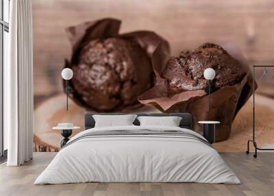 Delicious freshly baked chocolate muffins on a wooden background. Delicious cupcake close-up. The context of a bakery with pastries. Confectionery products. Wall mural