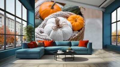 Still-life. Knitted pumpkin, orange pumpkins, beige knitted plaid in a homemade wicker basket. Cozy autumn concept. Home decor. Wall mural