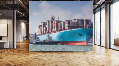 Towing a large container ship at the seaport. Tugboats pushing a container ship. Many containers on the deck of the ship. Loaded ship Wall mural